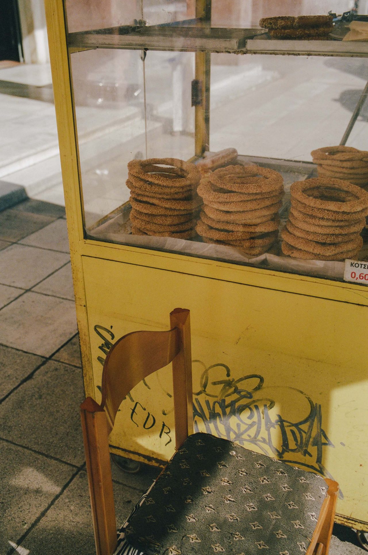 A close-up of an outdoor vendor cart filled with koulouri (a type of bread with sesame seeds)
